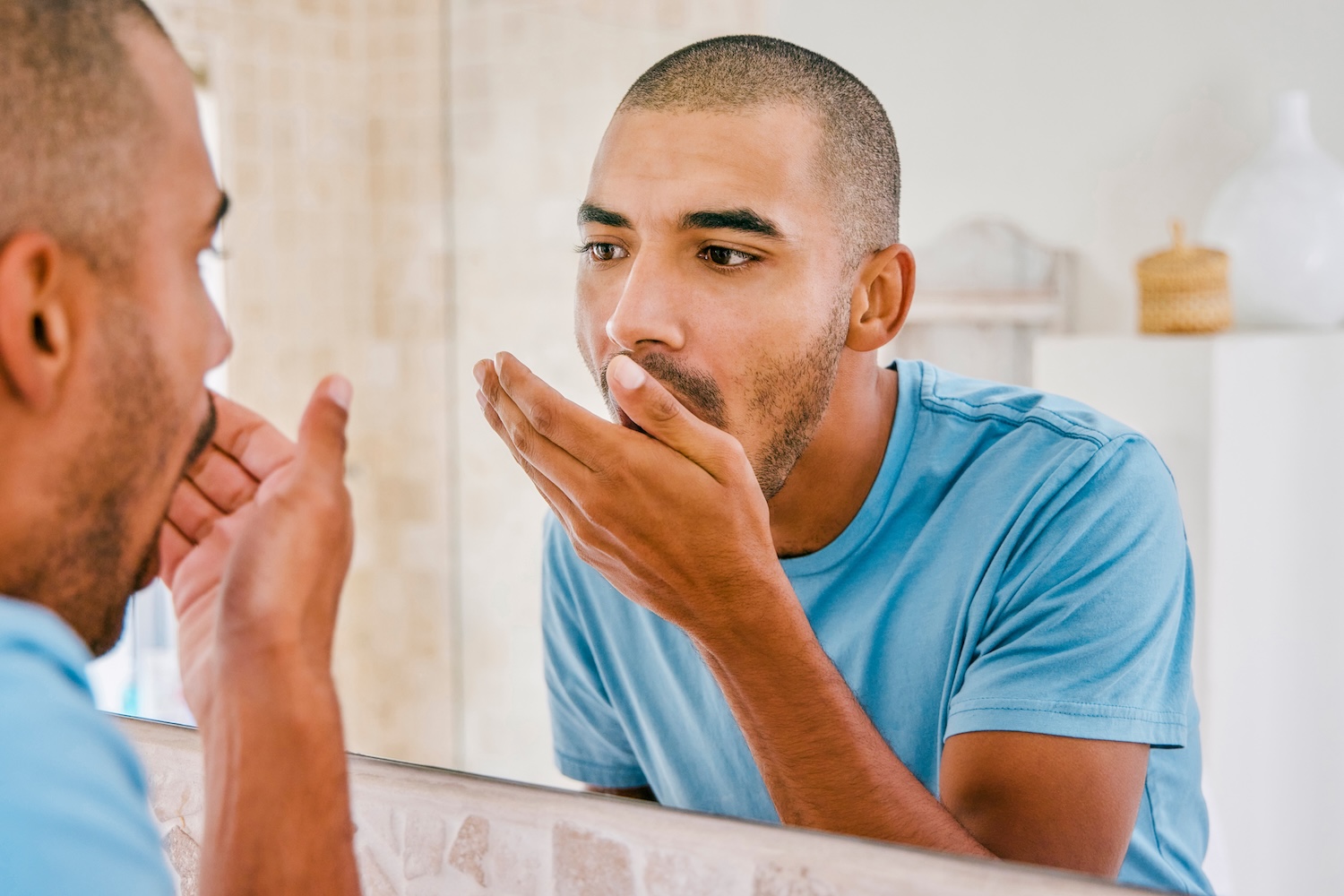 man with bad breath, halitosis checking his breath in the bathroom